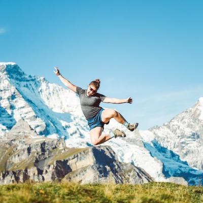 student jumping into the air in Sweden, snowy mountains behind 